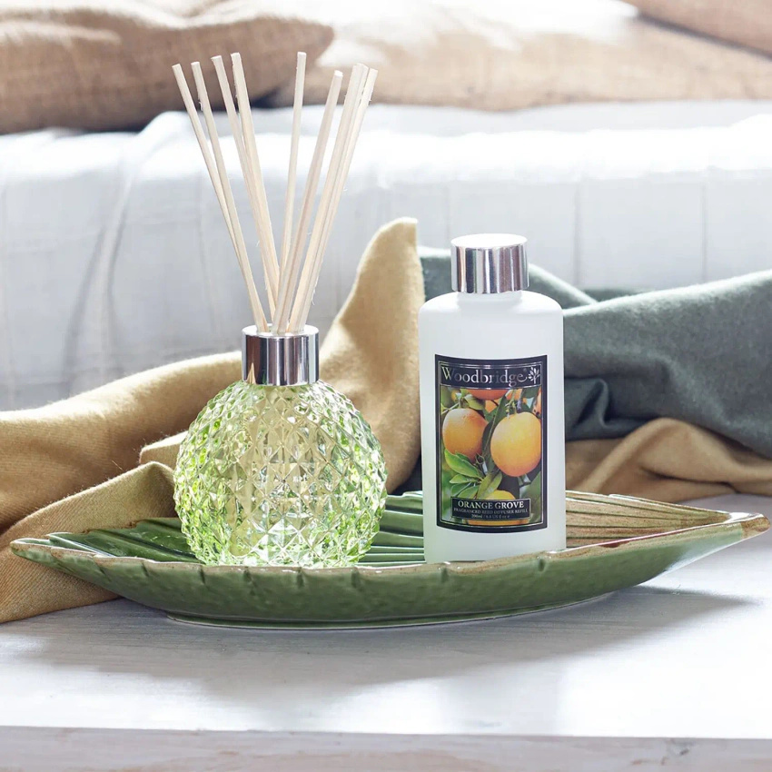 Bottiglia vuota verde con bastoncini diffusori in una scatola di Woodbridge Candle
